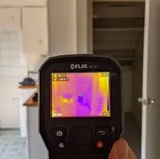 Handheld thermal camera displaying temperature differences inside a property